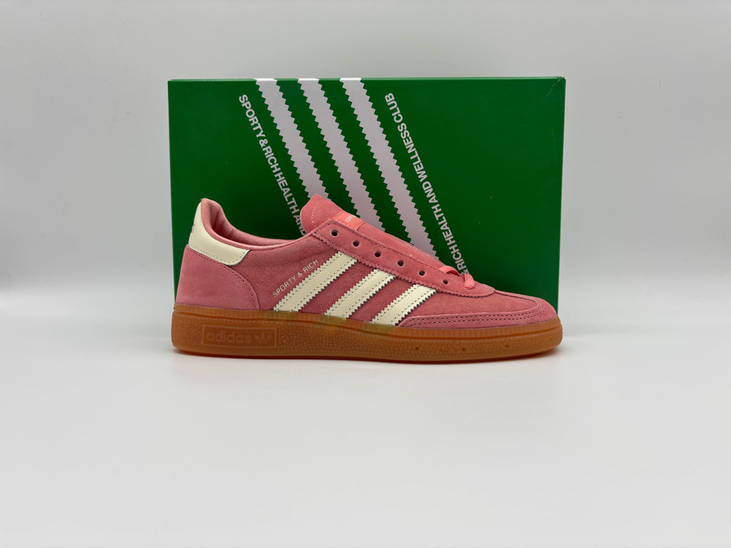 Side view of Adidas Handball Spezial Sporty & Rich Pink sneakers with low-top design, leather upper in soft pink, and rubber sole for retro style and streetwear flair.

